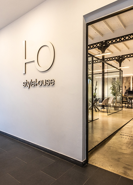 Accés a l’oficina de StyleHouse Terrassa amb logotip a la paret i interior modern amb parets de vidre i llum natural