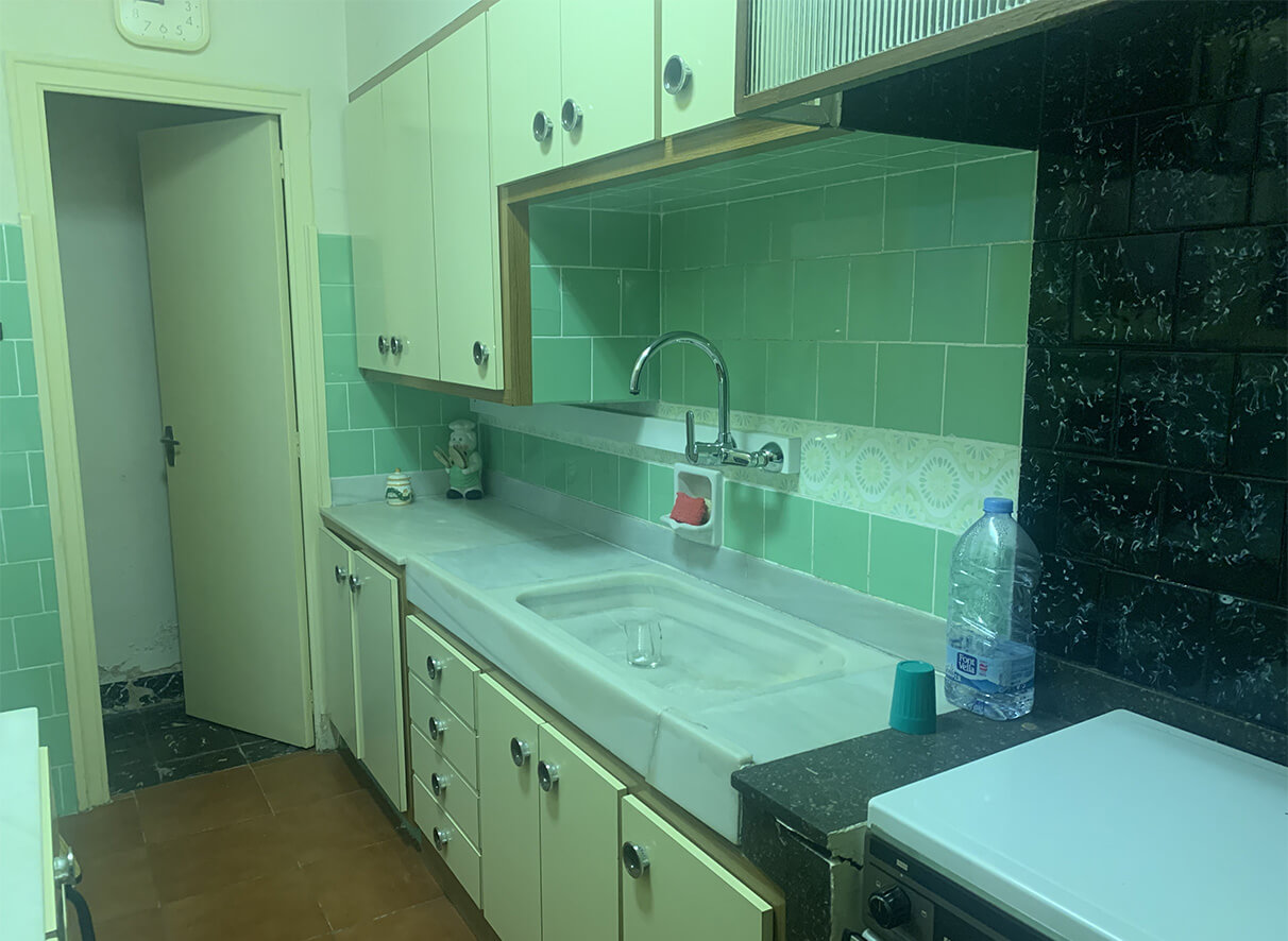 Cocina antigua con azulejos verdes y muebles clásicos antes de la renovación integral realizada por Stylehouse en Terrassa.